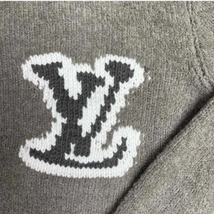 Grå stickad tröja LV - Säljer en stilren grå stickad tröja med en stor vit och svart logotyp på ryggen. Tröjan har långa ärmar och ribbade muddar vid ärmslut och nederkant. Perfekt för kyliga dagar!