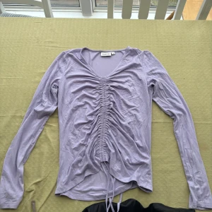 Ljuslila långärmad topp från Kappahl  - Säljer en ljuslila långärmad topp från Kappahl med v-ringning och snörning framtill. Perfekt för en stilren look med en twist. Passar bra till både jeans och kjol. Har aldrig använt den💕