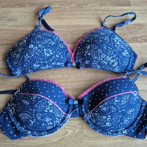 2 st nya bh från Esprit storlek 75AA - Säljer två stycken söta blå behå:ar med blommigt mönster och rosa spetsdetaljer från Esprit. Den understa är en klassisk bygel-bh med uttagbara kuddar och pyttelite vaddering. Den andra är en mjukisbehå med tunna trekantskupor. Bägge i storlek 75AA. Den har rosa spetsdetaljer och en liten rosett framtill. Perfekt för att lägga till lite färg i garderoben! Bägge är nya och helt oanvända. Kommer från ett konkurslager. Kan skickas eller hämtas centralt i Malmö. Om priset är för högt kom med bud.