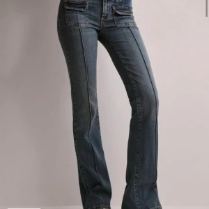 Blå bootcut jeans - Snygga blå bootcut jeans med låg midja och dubbla knappar fram. De har framträdande fickor både fram och bak, original pris 700kr