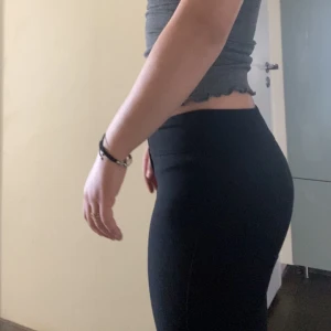 Svarta byxor med låg midja - Snygga svarta byxor med låg  midja och en tight passform. Byxorna har en klassisk design med dragkedja och knappar framtill. Perfekta för en stilren look.