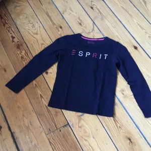 Mörkblå långärmad tröja från Esprit - Säljer en snygg mörkblå tröja från Esprit med lång ärm och tryck i rosa och vitt på framsidan. Perfekt för en stilren och bekväm look. Passar barn i åldern 8-9 år.