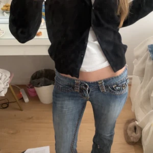 Lågmidjade jeans med broderade detaljer - Snygga blå jeans med låg midja och unika broderade detaljer på bakfickorna. Jeansen har en bootcut och är verkligen så fina, har defekter längst nere eftersom de har varit för långa och då blivit trampade på, fråga om foto ifall intresserad❤️