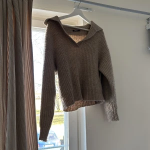 Beige stickad tröja med v-ringning - Säljer en mysig beige stickad tröja med v-ringning och långa ärmar från Gina Tricot. Tröjan har en ribbad struktur och en lös passform.