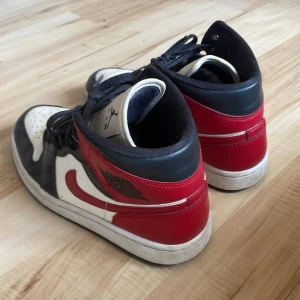 Nike Air Jordans i svart, vitt och rött - Säljer ett par klassiska Nike Air Jordans i svart, vitt och rött. Skorna har snörning och den ikoniska Air Jordan-loggan på sidan. Perfekta för dig som älskar sneakers med stil och komfort.