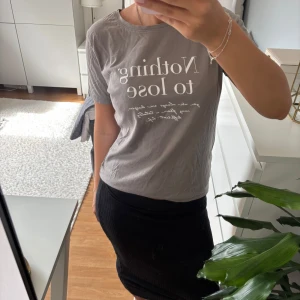 Grå t-shirt med tryck  - Snygg grå t-shirt från New Yorker med vit text på bröstet: 'Nothing to lose'. Klassisk rund halsringning och korta ärmar. Skön och lätt i bomull, perfekt till jeans eller kjol. Enkel och stilren vibe.