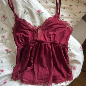 Vinröd linnetopp med spetsdetaljer - Supersöt vinröd linnetopp med tunna axelband och spets längs urringning och nederkant. Säljer pga den inte kommit till användning 💘