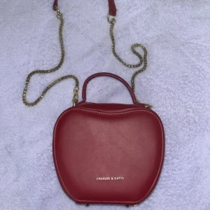 Äppelformad väska  - Äppelformad axelrems väska, märket Chasler, köpt i Irak. Bara bärt den några par gånger. 