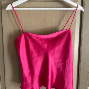 Rosa satinlinne från Gina Tricot - Supersnyggt rosa linne från Gina Tricot i glansig satin med tunna axelband. Enkel och stilren modell som ger en fräsch vibe till din outfit. Perfekt för dig som gillar färg och vill sticka ut lite extra.