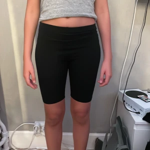 Svarta cykelshorts från H&M - Svarta cykelshorts från H&M i stretchigt material. De är tighta och midwaist, perfekta för träning eller chill. Klassisk modell utan detaljer, sitter skönt och följsamt. Passar dig som gillar enkel och sportig stil.