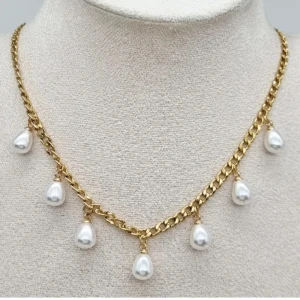 Guldhalsband med droppformade pärlor - Stilrent halsband i guldtonad kedja med sju droppformade vita pärlor som hänger längs hela halsbandet. Perfekt för dig som vill ha en elegant och trendig accessoar med lite extra bling.