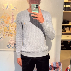 Ljusblå kabelstickad tröja Morris M - Snygg ljusblå kabelstickad tröja från Morris med rund hals och diskret broderad logga på bröstet. Tröjan är i väldigt fint skick och bara använd ett fåtal gånger. Tröjan är i strl M, bara att höra av sig om man har några frågor👍