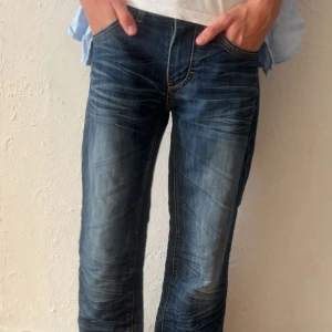 The modern art of vintage jeans - Snygga jeans i klassisk blå tvätt med slitningar och kontrastsömmar. Modellen har rak passform och normal midja, med fem fickor och gylf med knappar. Perfekta för en avslappnad och tidlös stil.