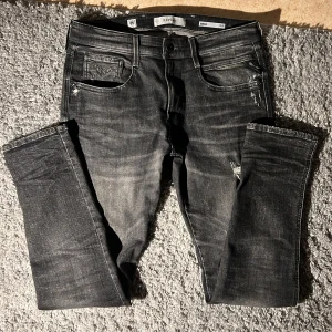 Replay Anbass jeans - Säljer ett par Replay Anbass slim fit jeans i svart tvättad denim med slitningar och snygga detaljer. Jeansen har klassisk femficksdesign, dragkedjegylf och smal passform. Perfekta för dig som gillar en modern och edgy look. Mycket eftertraktade svarta/grå replay anbass slim fit jeans. Storlek 33/32. Mycket bra skick. Nypris 1800kr. Mitt pris 500kr. Kontakta mig om du har frågor✅👍