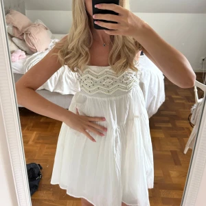 Vit kort klänning från Zara - Supersöt vit kort klänning från Zara med tunna axelband och broderade pärldetaljer upptill. Klänningen har en luftig, flowy passform och är perfekt för varma dagar. Materialet känns lätt och somrigt, och toppen har ett snyggt mönster med pärlor.
