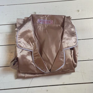 Champagnefärgad satinpyjamas 🩷 - Snygg champagnefärgad pyjamas i satin med långärmad skjorta och matchande byxor😍Skjortan har svarta knappar, vit piping och en bröstficka. Materialet är glansigt och mjukt, perfekt för chillkvällar hemma. Den är i nytt skick, säljer eftersom den inte kommit till användning. Nypris 700kr men köpt på rea. Byxorna är i storlek S och skjortan i M men skulle säga att den passar s med💕