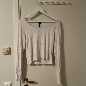 Vit långärmad topp med spetskant - Söt vit långärmad topp från lager 157 med croppad passform och fin spetskant runt den breda urringningen. Tillverkad i mjuk bomull, perfekt att styla med jeans eller kjol för en clean look. Katt finns i hemmet 