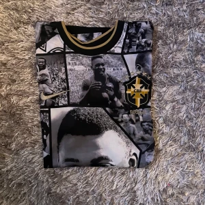 Brasil Pelé fotbollströja Nike svart - Unik svart Brasil-fotbollströja från Nike med collage av klassiska svartvita foton på framsidan, gulddetaljer vid hals och ärmslut, CBF-emblem och Pelé 10-tryck på ryggen. Tillverkad i mjukt, sportigt material. Perfekt för dig som älskar fotbollshistoria.