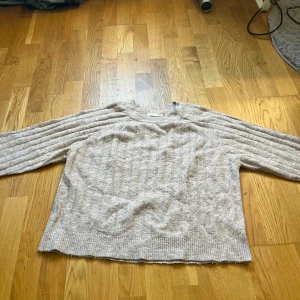 Beige stickad tröja från 157 XS - Mysig beige stickad tröja från 157 i storlek XS. Tröjan har ett ribbat mönster både på ärmar och kropp, rund halsringning och långa ärmar. Perfekt för lager-på-lager och chill höst- och vinterstil.