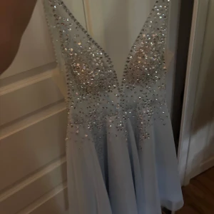 Ljusblå kortklänning med paljetter - Superfin ljusblå kortklänning med djup v-ringning och massor av glittriga paljetter upptill. Special gjord, aldrig använd. Pris kan diskuteras 