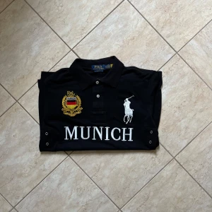 Chief keef polo Munich - Svart pikétröja från Polo Ralph Lauren med stor vit logga och texten MUNICH på bröstet. Broderad gul och röd detalj på vänster sida, samt stor siffra 5 på ryggen och ärmen. Klassisk krage och korta ärmar. Tillverkad i mjuk bomull. Pris kan diskuteras vid snabbaffär!