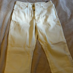 Vita raka jeans  - Snygga vita jeans raka ben och klassisk femficksdesign. Jeansen har hög midja, silverfärgade nitar och är gjorda i kraftig bomull. .