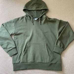 Olivgrön hoodie från Gina Tricot - Olivgrön hoodie från Gina Tricot med klassisk känguruficka och snörning i huvan. Tröjan har ribbade muddar vid ärmslut och nederkant, samt en relaxed look, sjukt skönt material inuti enligt mig själv, aldrig använd❤️