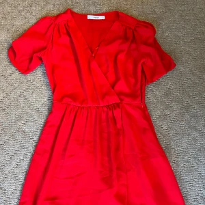 Röd omlottklänning från Mango - Röd långklänning från Mango med omlottmodell och korta puffärmar. Klänningen har v-ringning och är aldrig använd. Vill bli av med den då den inte används så prisförslag tas gärna emot🤍