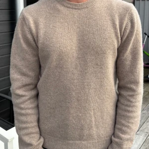 Beige stickad tröja Casual Friday M - Säljer en stilren beige stickad tröja från Casual Friday i storlek M. Tröjan har rund halsringning, ribbade muddar och är långärmad. Perfekt för lager-på-lager och passar till både jeans och chinos.