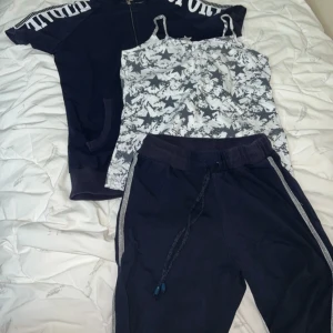 Mörkblå sportig set med dragkedja - Sportig mörkblå set med korta ärmar, hel dragkedja och mesh-tyg på ryggen för extra ventilation. Stora vita tryck på axlarna och en stjärndetalj framtill. Perfekt för träning eller chill dagar. 