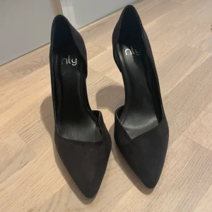 Klackskor - Stilrena svarta klackskor från nelly med spetsig tå och hög klack. Skorna är i mocka-look och har en klassisk siluett som ger en snygg och elegant vibe. Perfekta för dig som gillar en clean stil. Väldigt bekväma men tyvärr är de försmå för mig. Helt nya. 