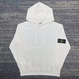 Vit hoodie från Stone Island - Vit hoodie från Stone Island med klassisk huva och snörning. Tröjan har en stor magficka och den ikoniska loggan på vänster ärm. Perfekt för dig som gillar en clean och stilren look.