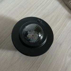 Stjärnhimmel lampa -  Bilderna visar en stjärnprojektor/lampa som skapar färgglada ljuseffekter i ett rum, perfekt för att skapa mysig stämning eller festkänsla. Produkten har flera knappar och USB