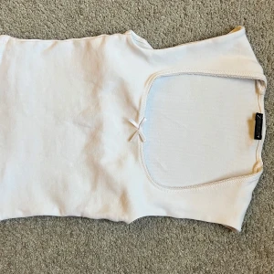 Vit ärmlös topp med rosett från Zara - Supersöt vit topp från Zara i storlek M. Modellen är ärmlös med en fyrkantig halsringning och en liten rosett framtill som ger en gullig touch. Materialet är mjukt och stretchigt💞💞