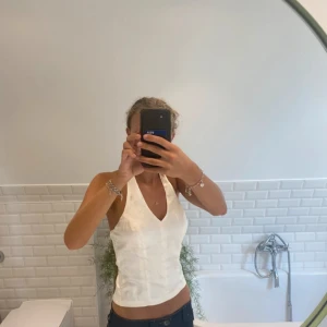 Vit satin topp - Säljer denna fina vita satintopp som man knyter i nacken. Eftersom man knyter den själv kan man välja hur högt upp urringningen ska sitta och hur croppad den ska vara nertill:) Den har även en dragkedja på sidan så den blir lätt att ta på och av. Storlek S. (Behöver strykas) Bara att skriva vid frågor eller funderingar💕