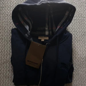 Mörkblå Burberry hoodie med dragkedja - Zip up tröja från Burberry, helt ny. Säljer den pågrund av att den är för liten för mig.  Tar emot byten på tröjan