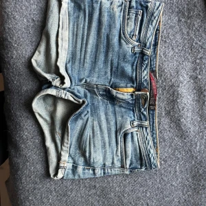 Blå jeansshorts från Zara - Snygga blå jeansshorts från Zara med klassisk femficksdesign och slitna detaljer. Modellen har normal passform, dragkedja och knapp framtill samt bälteshällor. Perfekta för varma dagar och har en cool tvättad look som passar till allt.