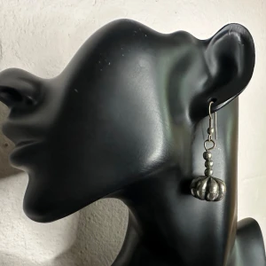 Retro Boho Örhängen i Silverfärgad Metall m Pumpaliknande Hängen Vintage 1980-tal 1990-tal Etno  -  Vackra vintageörhängen från 80/90-tal i boho/etnostil. Tillverkade i silverfärgad metall med dekorativa droppformade hängen som ger en rustik och tidlös look. Köpta second hand. 📏 Mått: ca 4,5 cm långa ✨ Skick: Fint vintagebruksskick med lätt patina. Nya gummistoppar. Jag använder dem inte längre och säljer därför vidare. Jag prutar inte, men erbjuder bundlerabatt. Jag rensar smyckesskrin och garderob – kolla mina andra annonser också!  ⸻ 