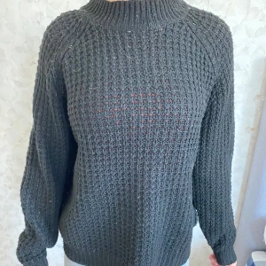 Svart stickad tröja från 157 - Säljer en svart stickad tröja från 157 i storlek S. Tröjan har grovstickat mönster, hög ribbad hals och långa ärmar. Perfekt för dig som gillar en chill och enkel stil med lite oversized känsla. Passar till jeans eller mjukisar för en avslappnad look.