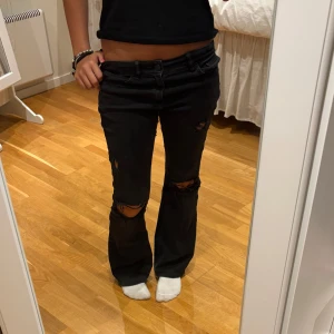 Svarta bootcut jeans med hål i knäna - Säljer ett par svarta bootcut jeans från Lindex. Storlek 164. 