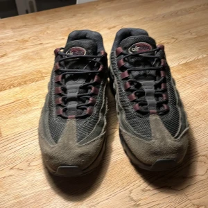 Nike Air Max 95  - Nike Air Max 95 sneakers med cool design i svart mesh och bruna mockadetaljer. Snygga vinröda snöröglor och synlig Air Max-sula ger en grym vibe. Perfekt för dig som gillar streetstyle och vill ha något unikt på fötterna.