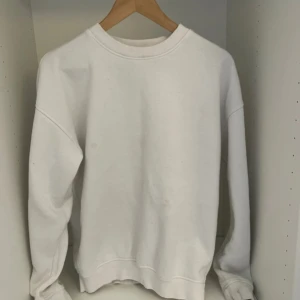 Vit sweatshirt  - En enkel vit sweatshirt med rund hals och långa ärmar. Tröjan har en klassisk loose passform och är tillverkad i mjuk bomull. Perfekt för chill dagar och passar till det mesta. Inga synliga loggor eller märken. Har dock några fläckar som ni kan se på bilden.