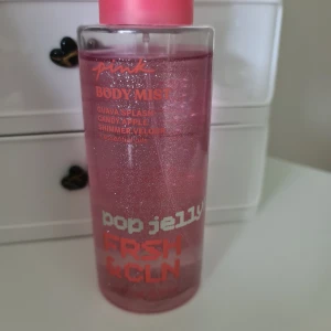 PINK Body Mist Pop Jelly - Body mist från PINK med doft av guava splash och candy apple. Flaskan är genomskinlig med rosa skimmer och har en rosa kork. Perfekt för dig som gillar fruktiga och söta dofter. Nästan full, endast använd några gånger se mängd på bilden.