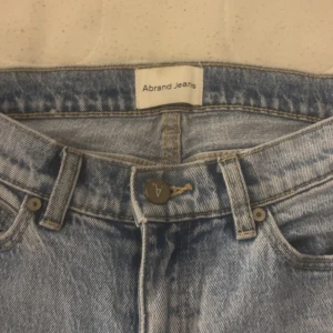 Abrand ljusblå bootcut jeans - Säljer ett par ljusblå jeans från Abrand Jeans med klassisk femficksdesign och bootcut-ben. Jeansen har låg midja. Använt fåtal gånger. Innerbenslängden är ca 68cm och passar mig perfekt som är 155. Köpte för 1500