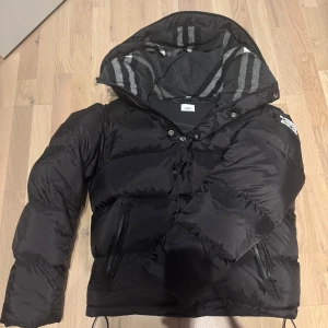 Ny jacka från Burberry - Säljer en svart pufferjacka från Burberry London England. Den är perfekt nu inför dem kalla tiderna och det kan även bli en väst. Säljer eftersom har massa andra jackor och denna bara ligger i garderoben. Vid frågor skriv till mig bara.