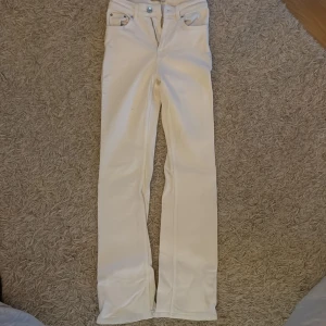 Full length jeans ginatricot vita - Snygga vita jeans med bootcut passform och medelhög midja. Klassisk femficksdesign och dragkedja med knapp framtill. Jeansen har raka ben med lätt utsvängning nedtill och är gjorda i ett stadigt denimtyg. Perfekta för dig som vill ha en clean och fräsch look. Knappt använda! Modellen är full length vilket har utgått från ginatricots sortiment. Strl 32.