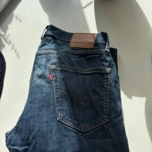 Levi's 502 mörkblå jeans - Snygga Levi's 502 jeans i mörkblå tvätt med klassiska fem fickor och brunt läderpatch bak. Jeansen har rak passform och är tillverkade i slitstarkt bomullsjeansmaterial. Perfekta för dig som gillar en tidlös och clean look.