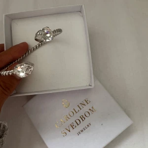 Silverfärgat armband Caroline Svedbom - Helt nytt armband i silverfärg från Caroline Svedbom med två stora, kristaller i droppform. Säljer då jag har dubblett av de. Nypris 800kr.