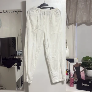 Vita linnebyxor med resårmidja - Säljer ett par fräscha vita linnebyxor med skön resår i midjan och stora fickor framtill. Byxorna har en rak passform och är perfekta för chill dagar eller när du vill ha en clean och enkel look. Materialet är lätt och luftigt, vilket gör dem nice för varmare väder.