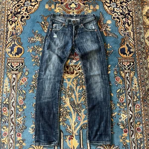 Lee mörkblå jeans - Snygga mörkblå jeans från Lee med bootcut passform och slitna detaljer för en cool vibe. Klassisk femficksdesign, kontrastsömmar och gröna fickfoder på insidan. Jeansen har låg midja och är gjorda i robust denim med dragkedja och knapp